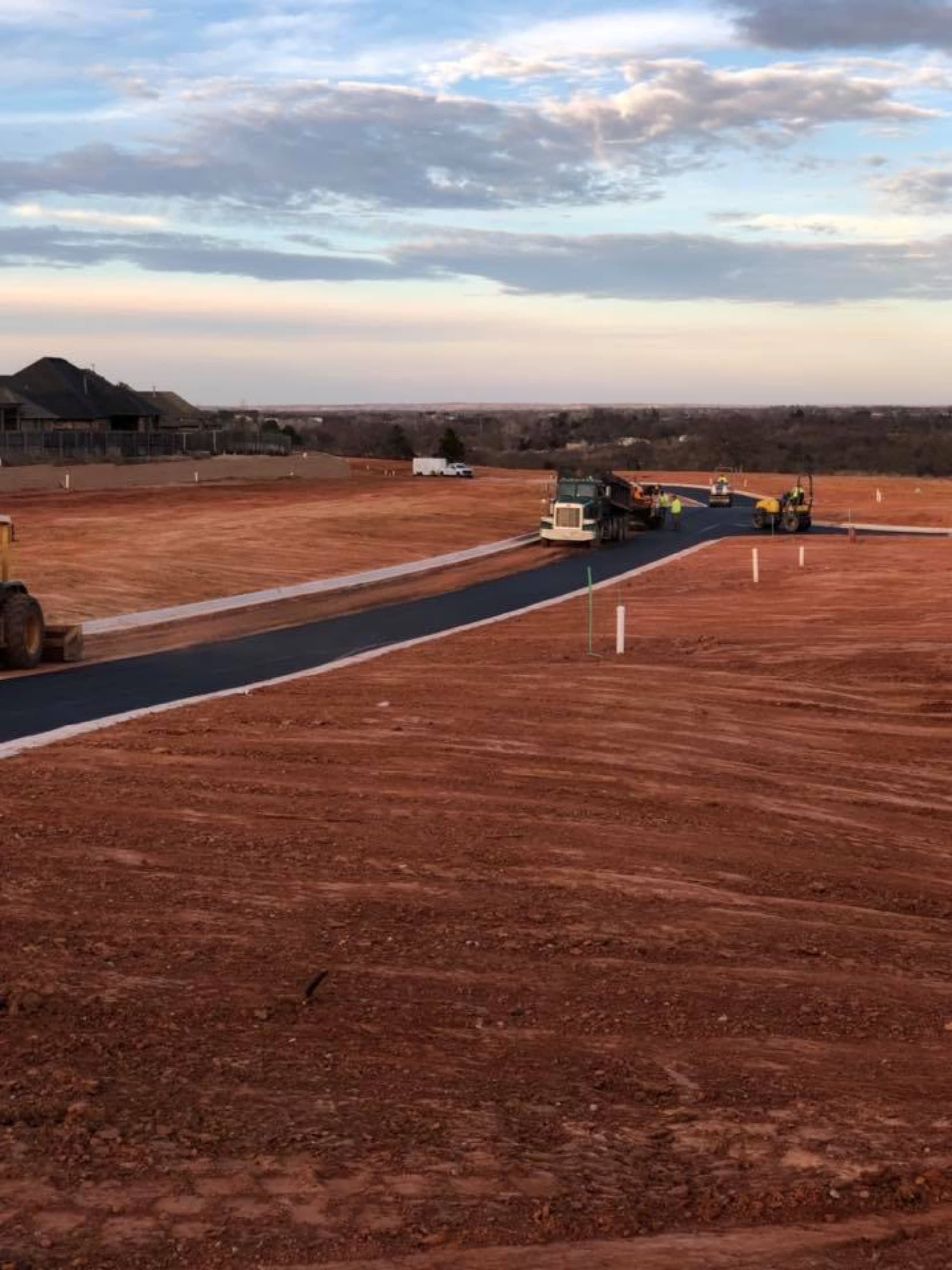 Asphalt paving crew working a subdivision at sunset