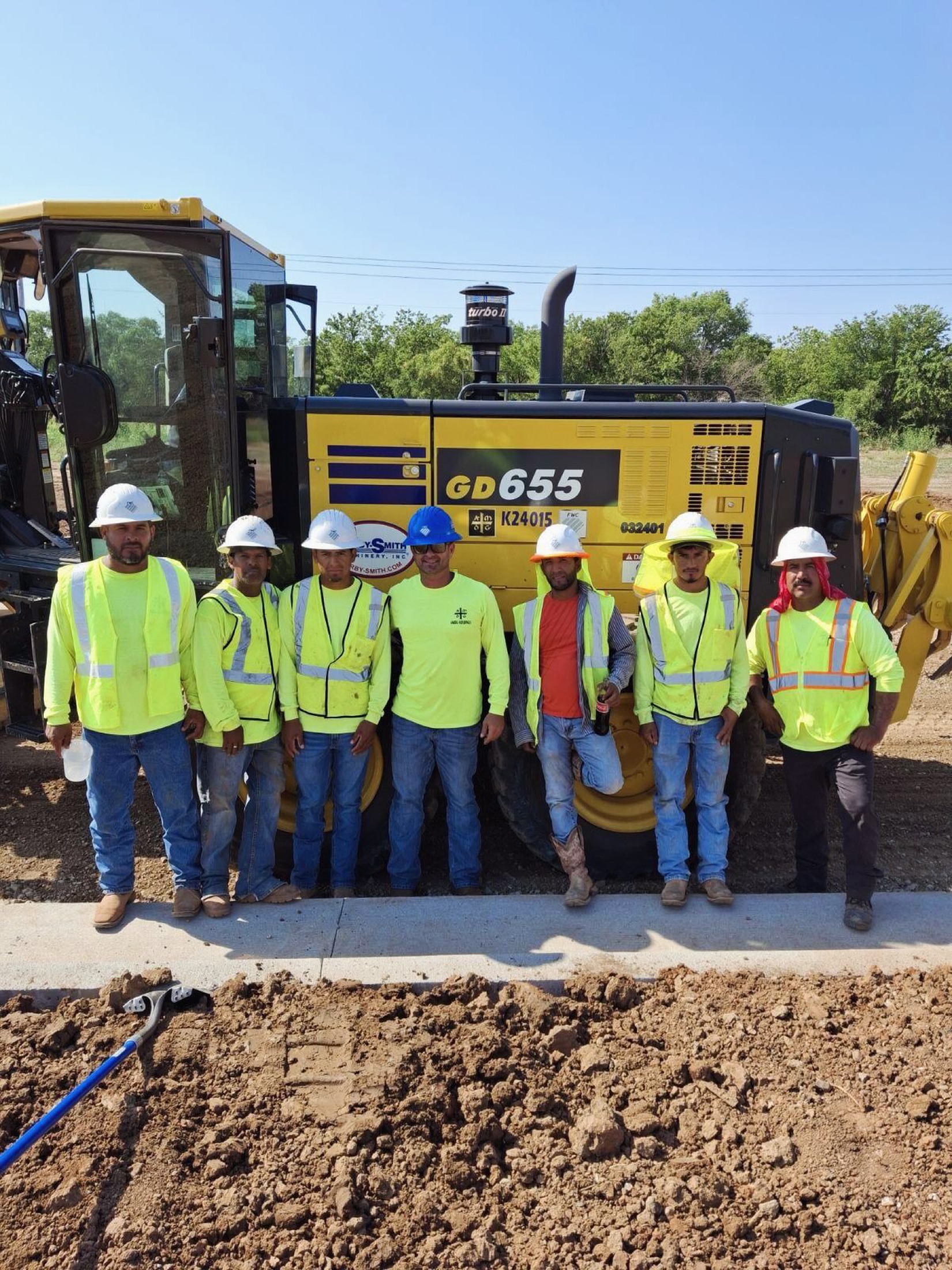 A First Water crew in hi-vis gear in front of a motor grader on an Oklahoma jobsite